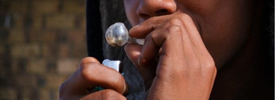 Person smokes meth out of a small glass pipe