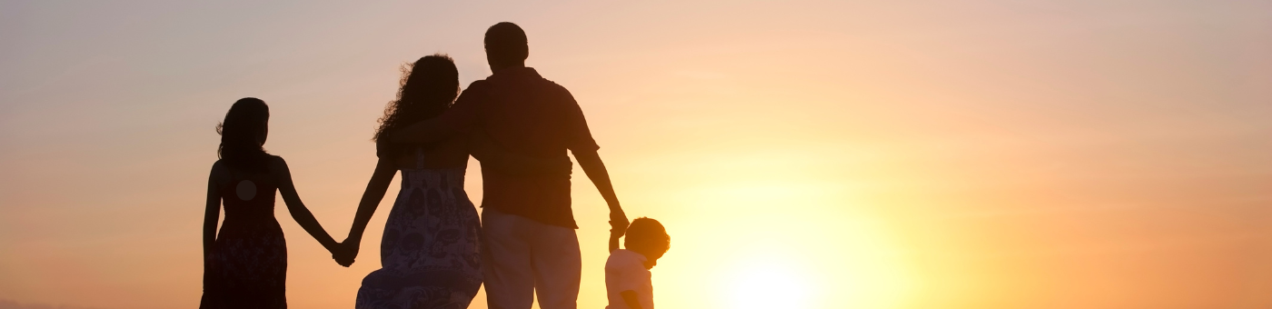 Silhouette of a family of four illuminated by sunlight.