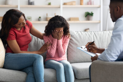 African american girl crying during therapy session with child psychologist