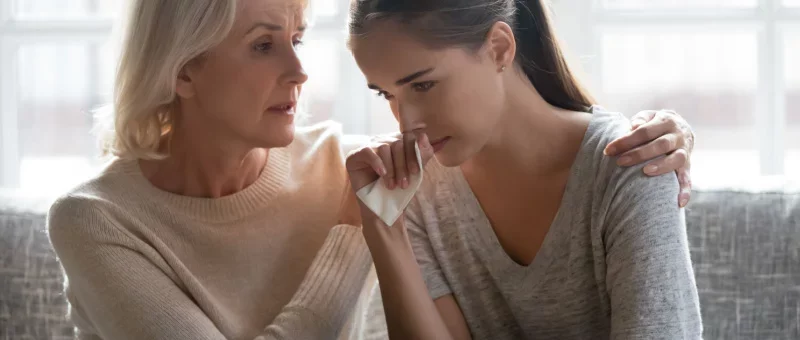 a young woman being comforted by another woman