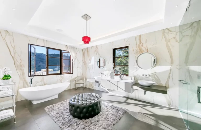 Modern bathroom with white marble walls, tub, sink, and canyon views